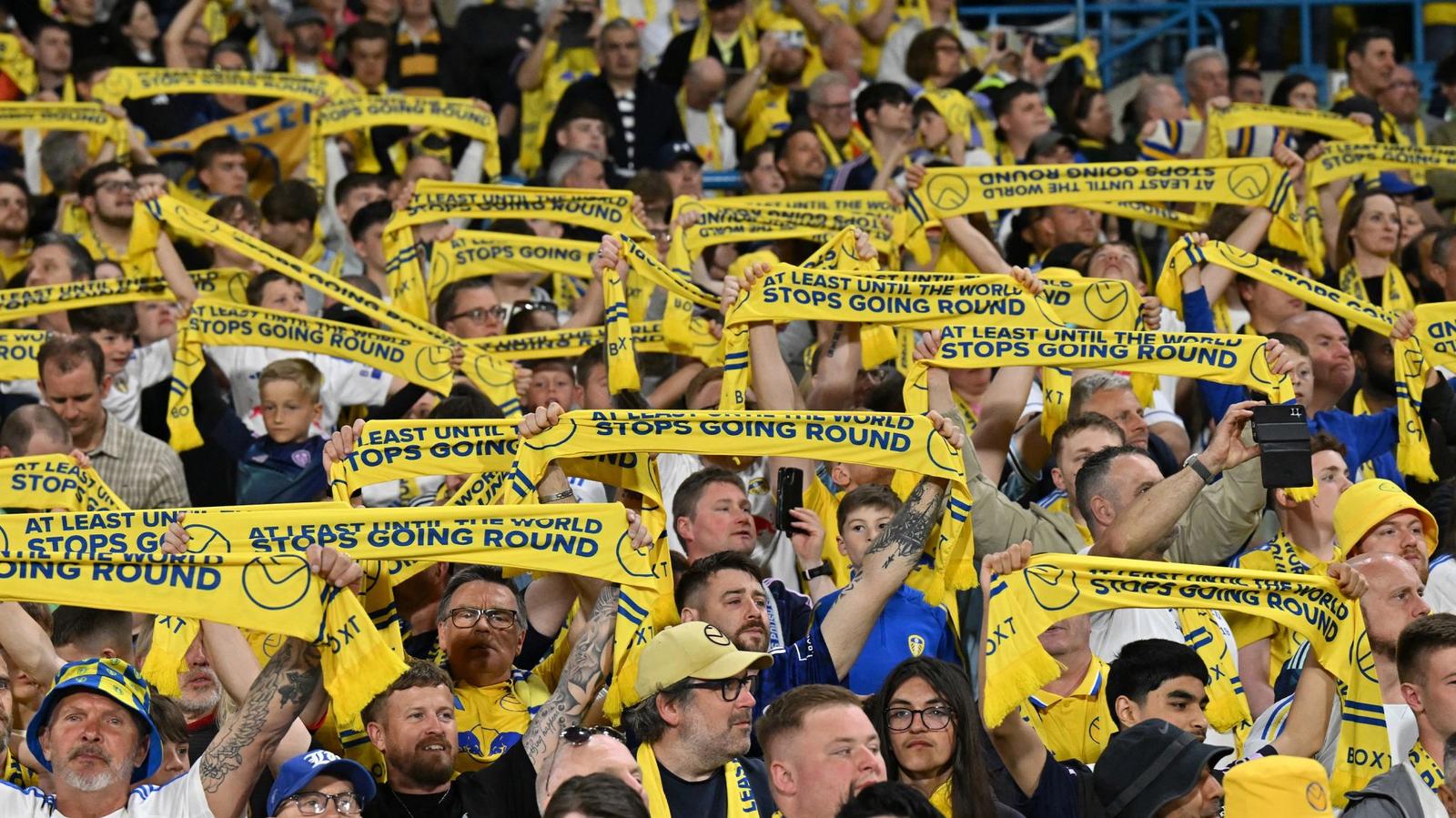 A stand full of Leeds United fans holding up yellow play-off scarves